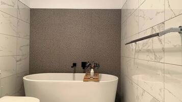 A modern bathroom with a freestanding bathtub, a toilet, and a towel rack.