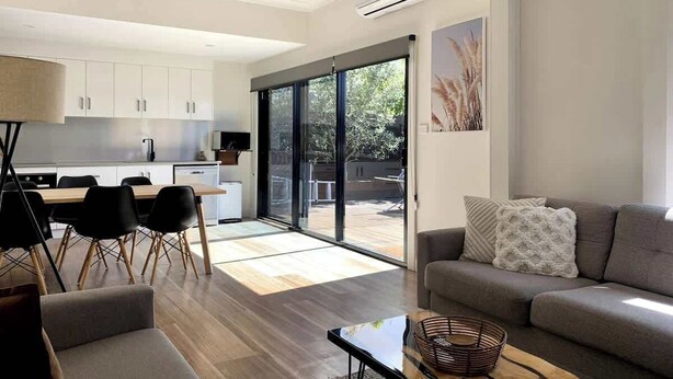 A modern living space with a dining area, a sofa, and a kitchen. - Renovated Character Home (Invermay)