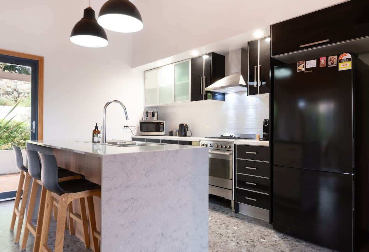 A modern kitchen with a central island, stainless steel appliances, and a black refrigerator.