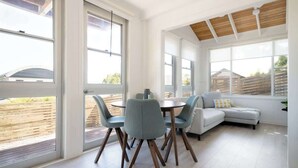 A modern interior with a dining area, a sofa, and large windows. - Little house on the hill (Riverside)