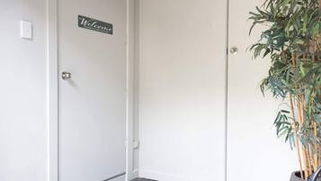 Una puerta con un letrero de 'Welcome', un felpudo y una planta en maceta.