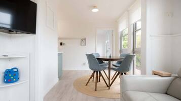 A modern dining area with a round table, chairs, and a flat-screen TV mounted on the wall.