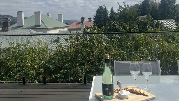 Une terrasse sur le toit avec une table dressée pour deux personnes, une bouteille de vin et un plateau de fromages.