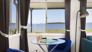 A room with a table, chairs, and a view of a lake. - Waterfront Cottage - direct waterfront access, boat-friendly block, firepit, water views (Swan Bay)