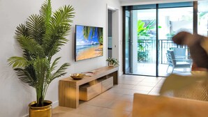 Una sala de estar moderna con un televisor de pantalla plana grande, un mueble bajo de madera y una planta en maceta.
