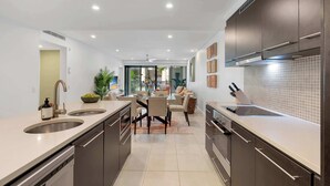 Una cocina moderna con armarios oscuros, una isla central y una zona de comedor con sofá y mesa.