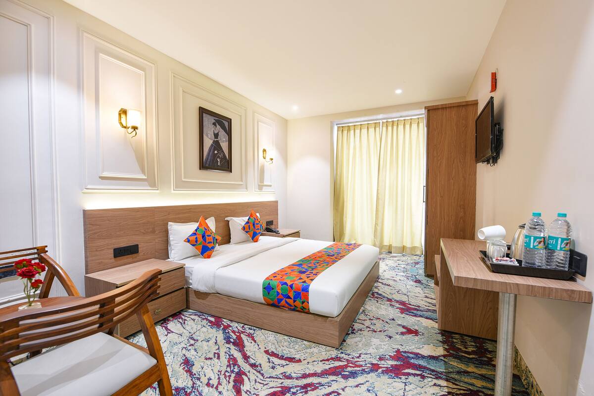 Une chambre d’hôtel comprenant un lit, une table de chevet, une chaise, un bureau et un téléviseur.