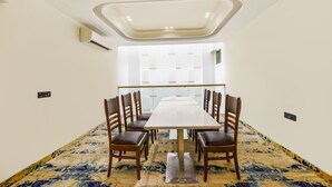 Une salle de conférence avec une longue table, des chaises en bois et un tapis à motifs.