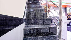 A staircase with black marble steps and a metal handrail. - Fabexpress Raj Palace (Mumbai)