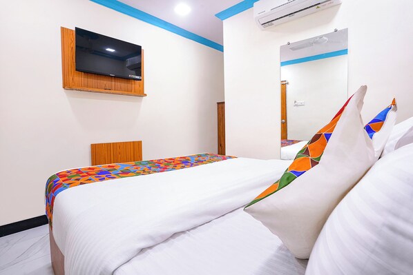 A hotel room with a bed, a TV mounted on the wall, and an air conditioning unit. - Fabexpress Raj Palace (Mumbai)