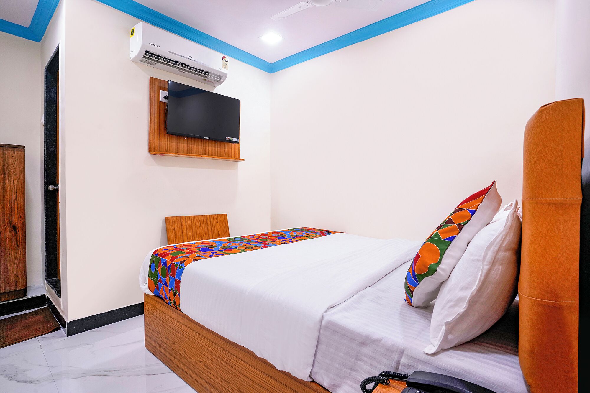 Una habitación de hotel con una cama, un televisor montado en la pared y una puerta.