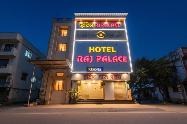 Un hôtel appelé Raj Palace, reconnaissable à son enseigne bien visible et à sa façade moderne.