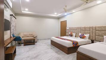 A hotel room with a bed, a sofa, a desk, and a ceiling fan.