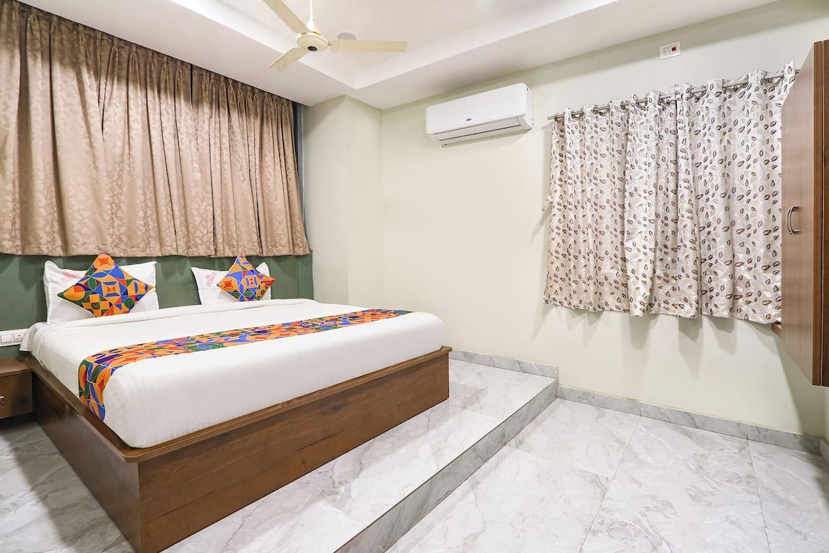 A bedroom with a bed, curtains, an air conditioning unit, and a ceiling fan.