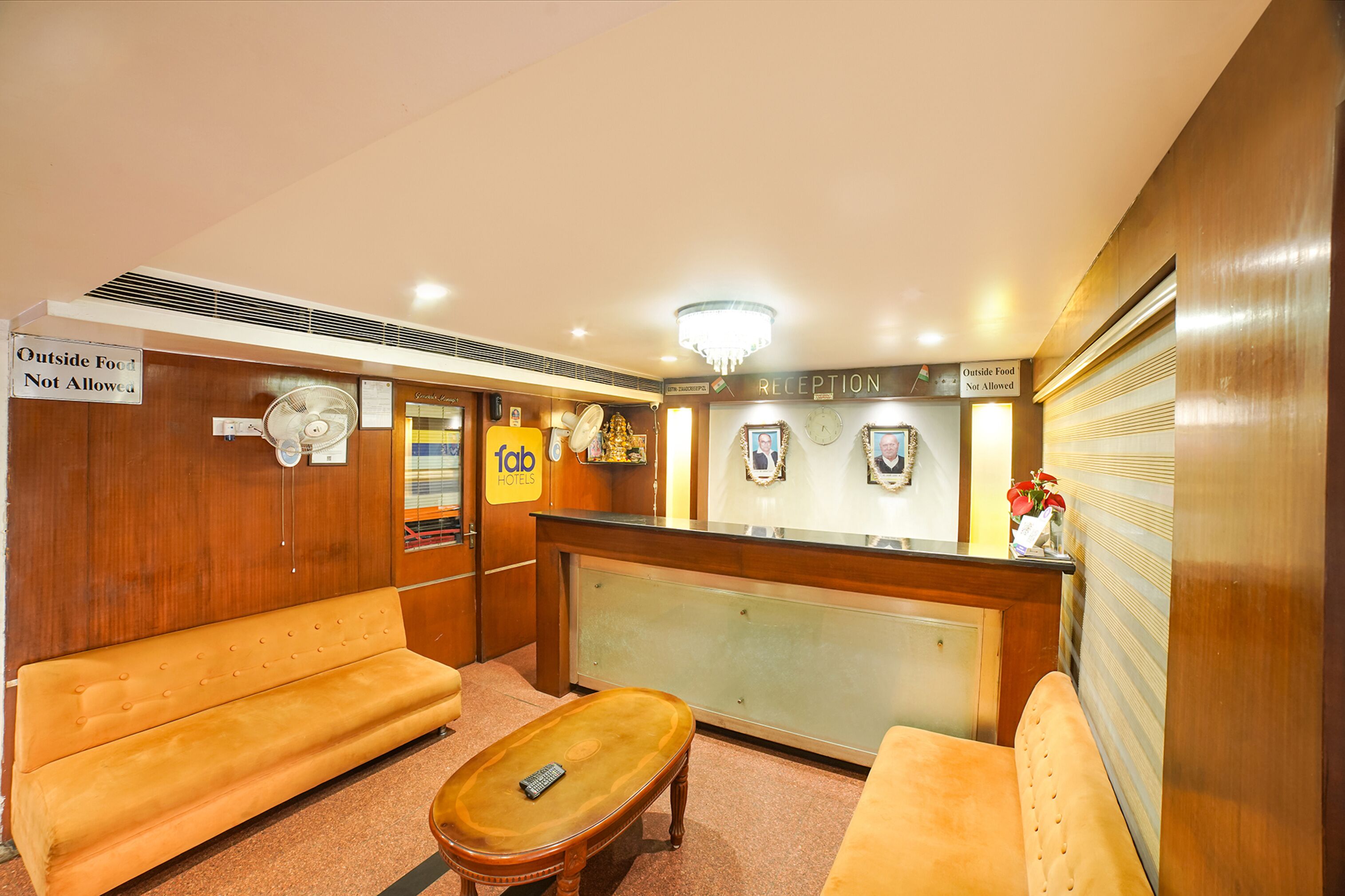 A reception area with wooden furniture, a reception desk, and signs indicating no outside food allowed.