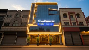 Un hôtel à la façade moderne, avec une enseigne bien visible indiquant « Hotel Pleasure Inn » et le logo « fabHOTELS ».