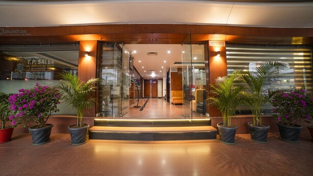 L’entrée d’un hôtel avec une façade en verre, un escalier menant au hall d’accueil et des plantes en pot.