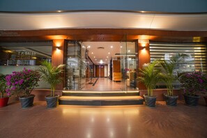 A hotel entrance with a glass facade, a staircase leading to the lobby, and potted plants. - Fabhotel Pleasure Inn (Bhopal)