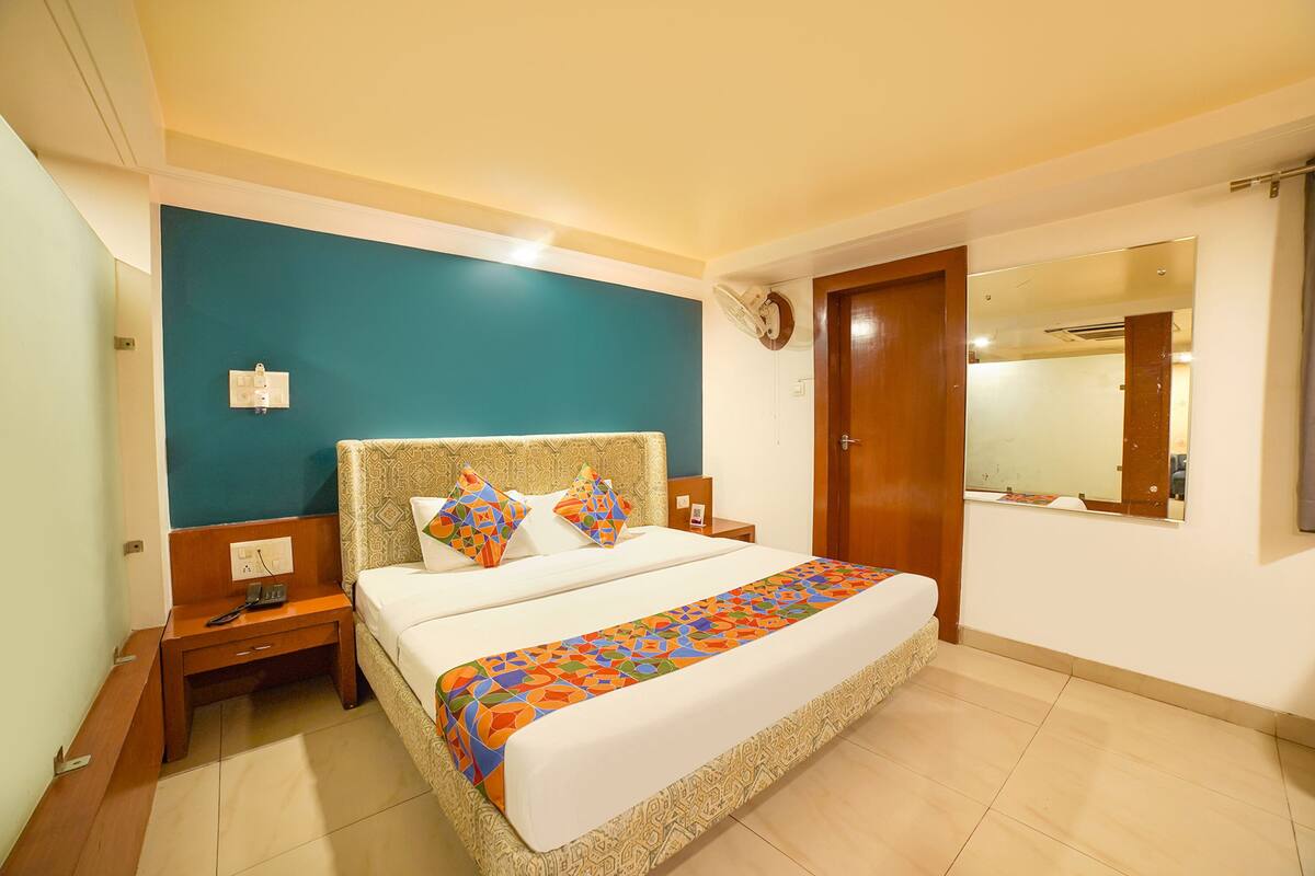 A hotel room with a bed, nightstands, a mirror, and a door.