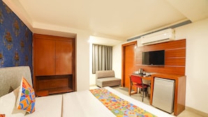 Une chambre d’hôtel équipée d’un lit, d’un bureau, d’une télévision et d’une armoire.