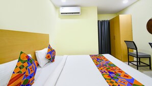 A hotel room with a bed, a desk, a chair, an air conditioning unit, and a wardrobe. - Fabhotel Living Tree (Hyderabad)