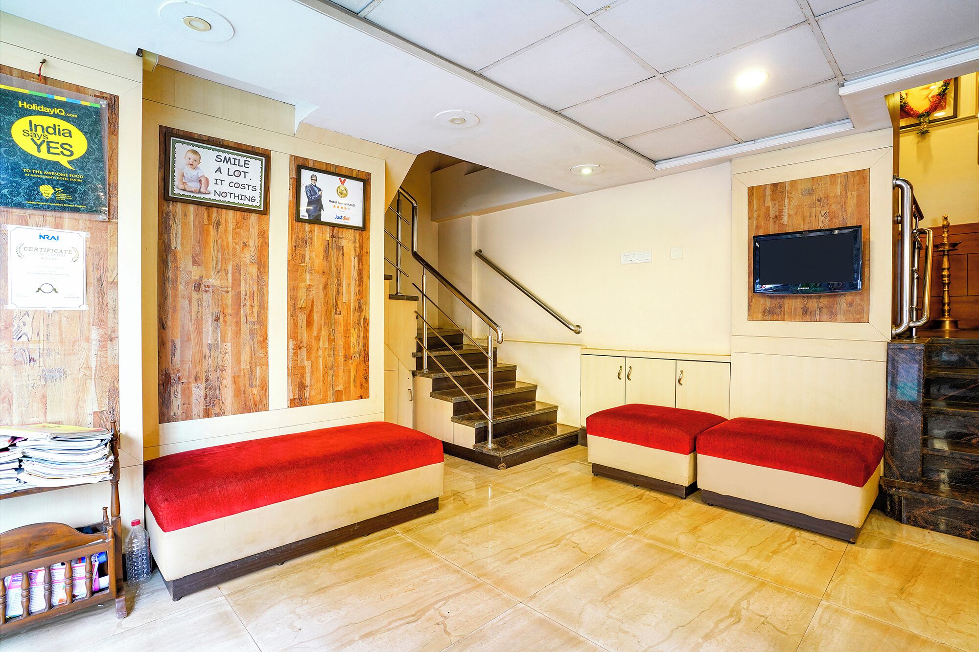 A hotel lobby with a staircase, wooden wall panels, and a red carpeted bench area.