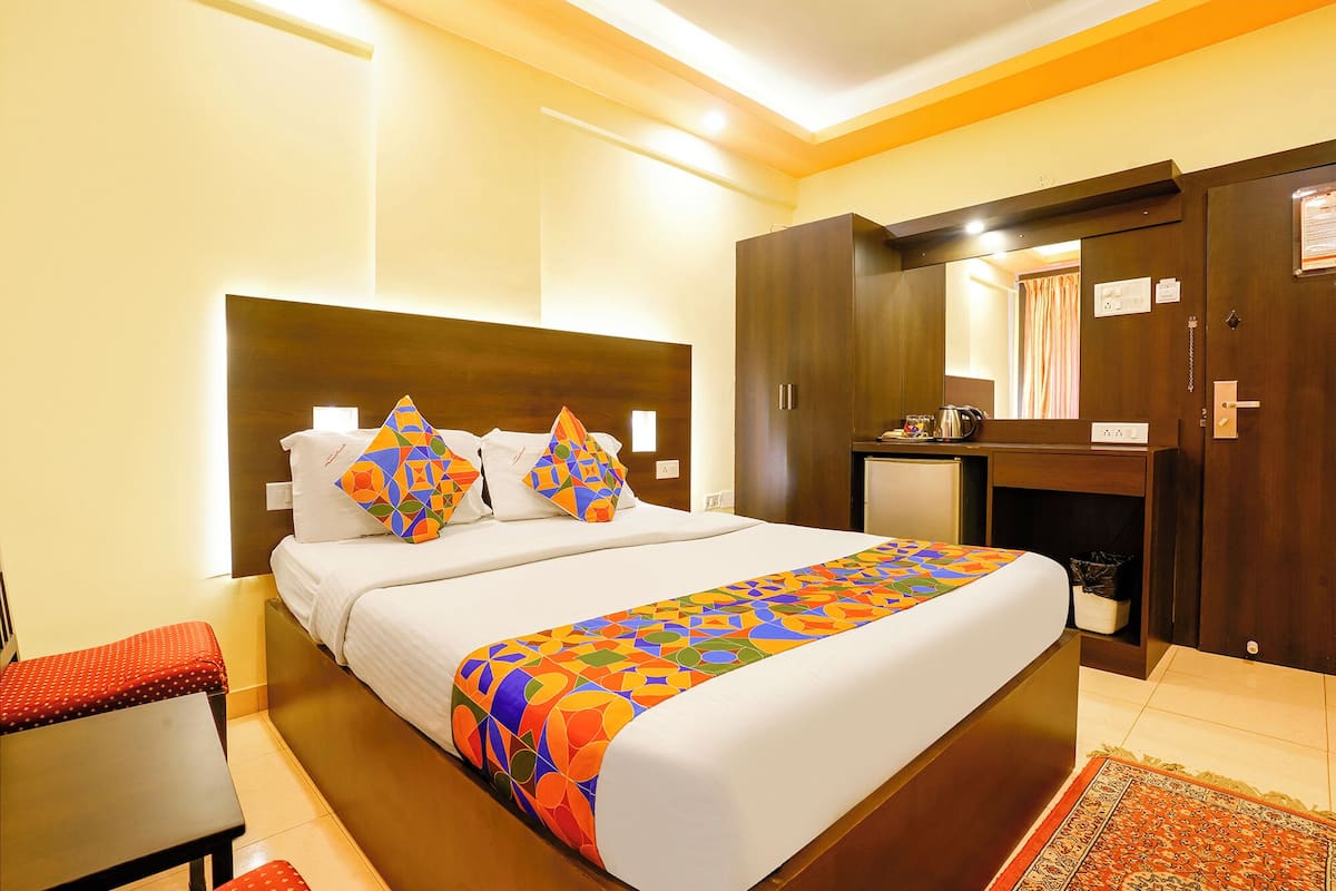 A hotel room with a bed, a desk, a wardrobe, and a mirror.