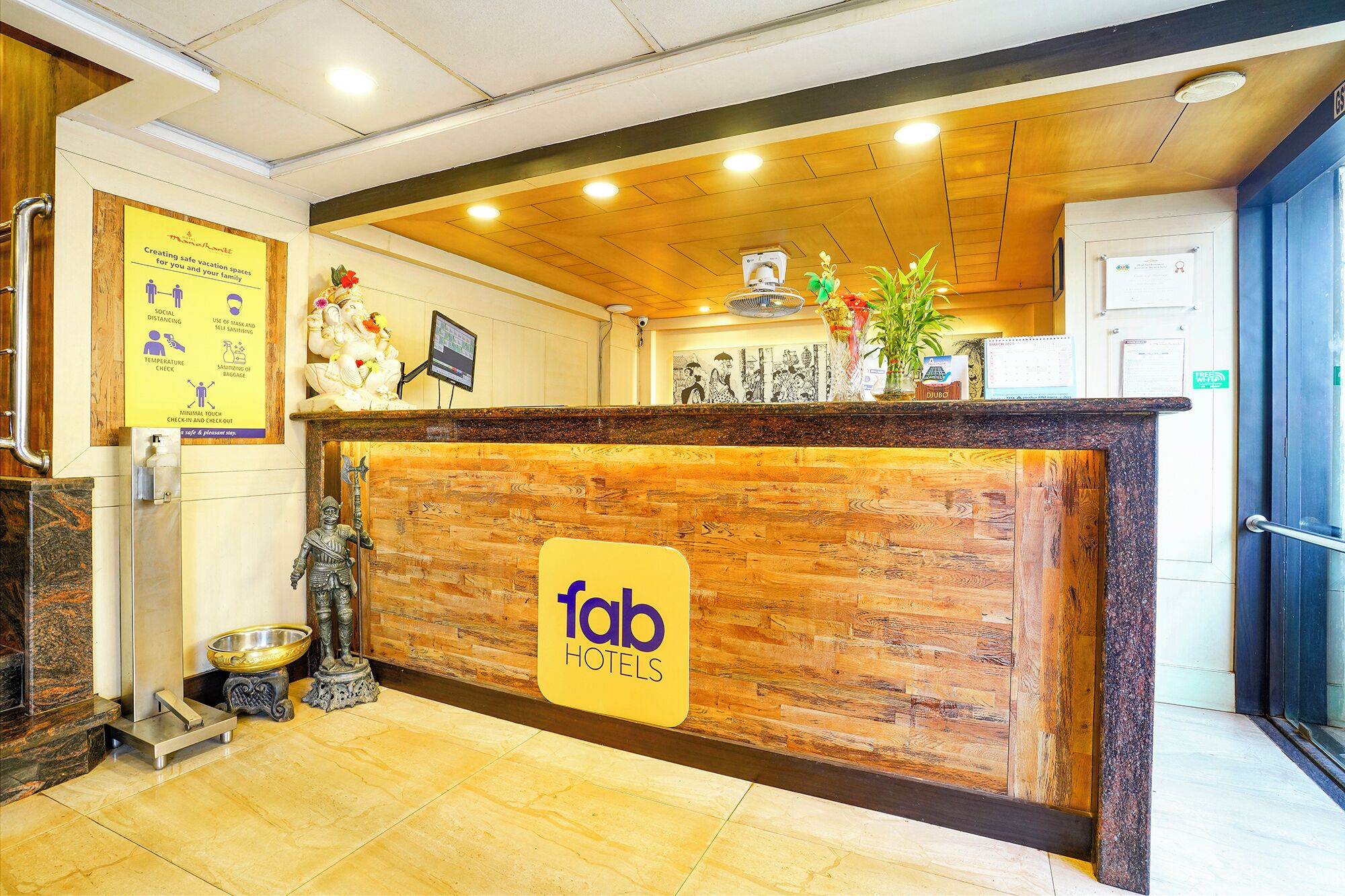 A reception desk with a wooden finish, a digital screen, and a sign reading "fab hotels".
