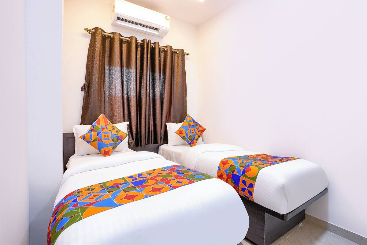 Quarto de hotel com duas camas, cada uma com um edredom de padrão geométrico colorido.