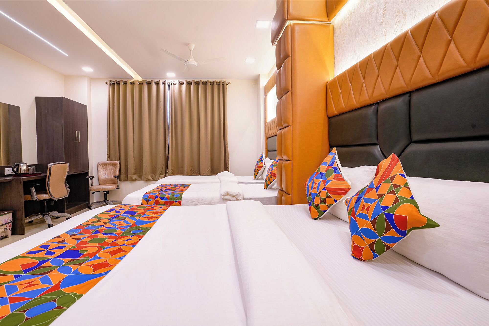 A hotel room with two beds, a desk, a chair, and a wardrobe.