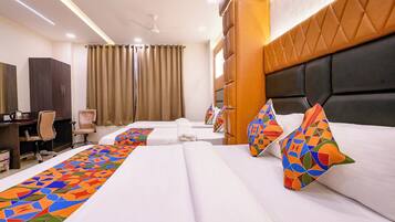 A hotel room with two beds, a desk, a chair, and a wardrobe.