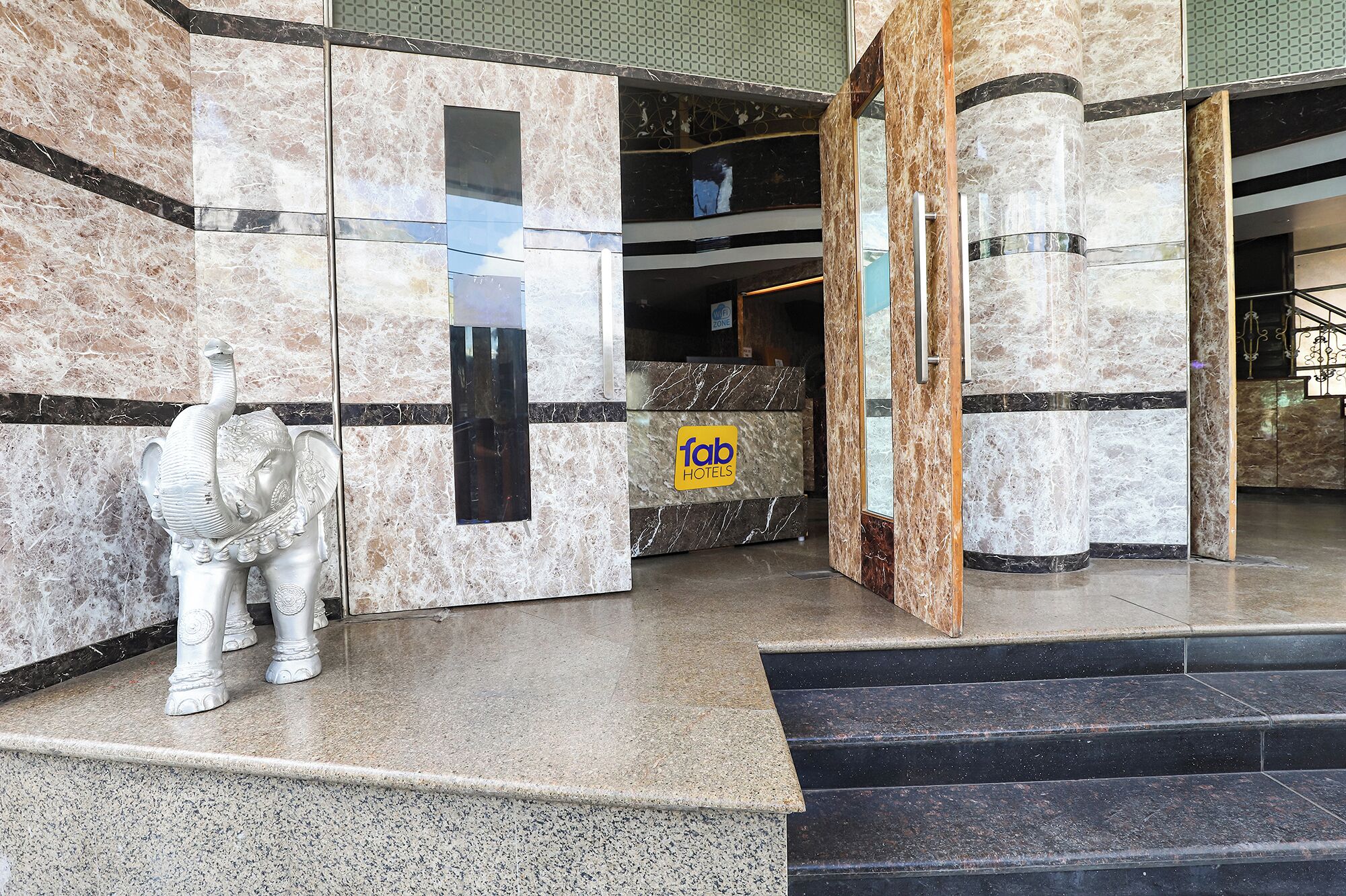 Un vestíbulo de hotel con paredes de mármol, un mostrador de recepción y una estatua de un elefante.