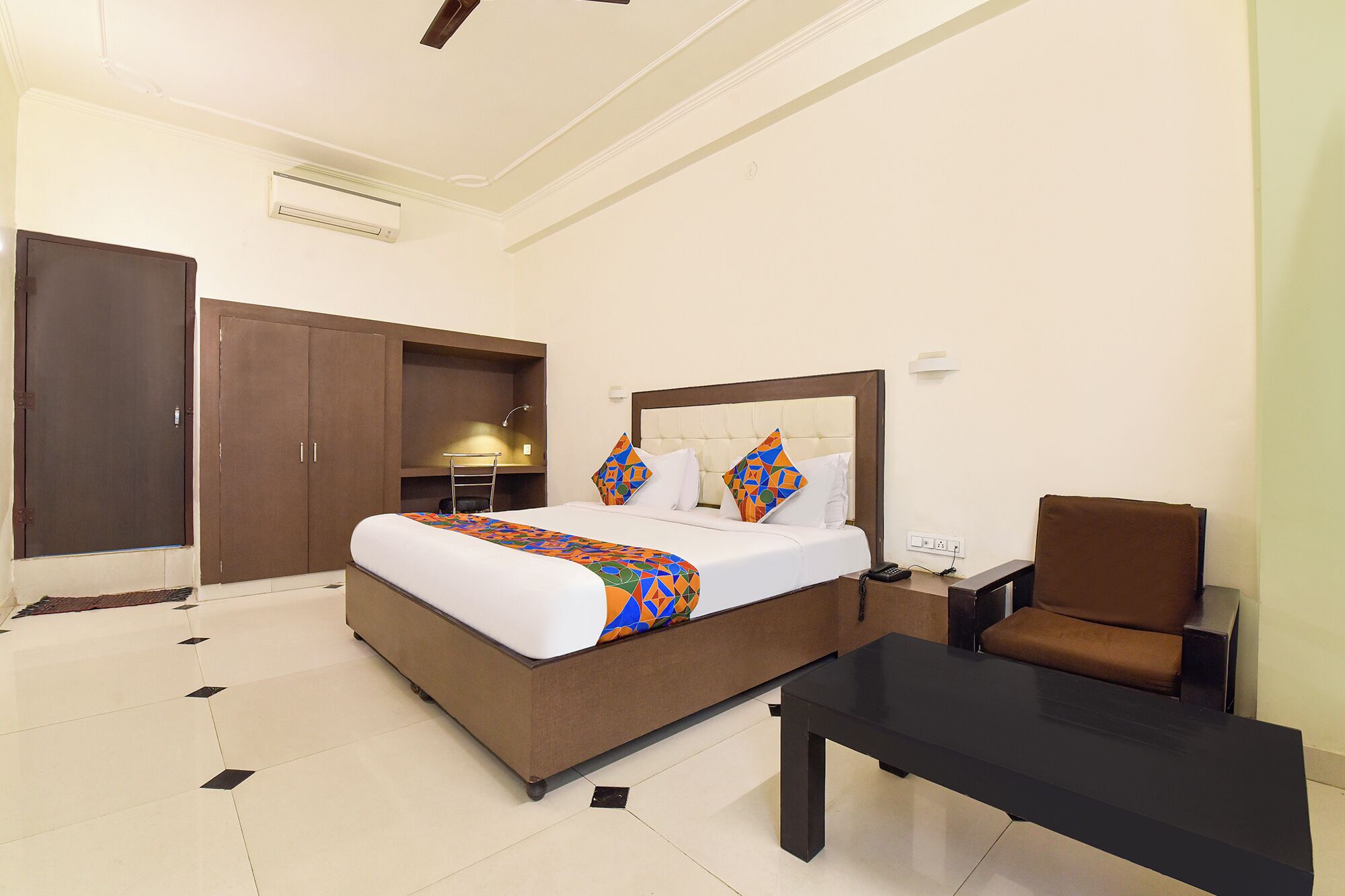 A hotel room with a bed, a desk, a chair, and a wardrobe.