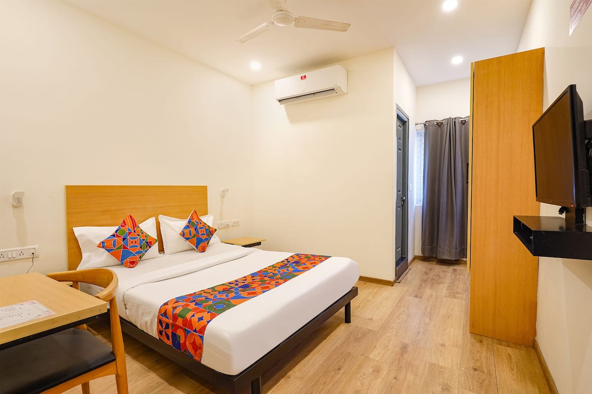 Une chambre d’hôtel équipée d’un lit, d’un bureau, d’une chaise, d’une télévision, d’un appareil de climatisation et d’un espace douche.