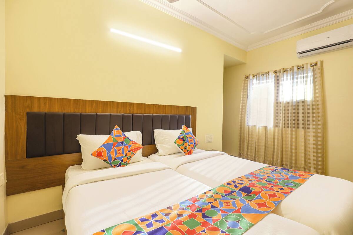Une chambre d’hôtel avec un grand lit, une tête de lit en bois et une couvre-lit aux couleurs vives.