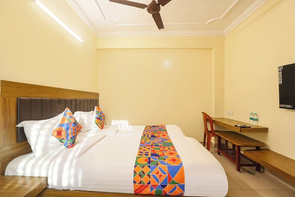 A hotel room with a bed, a desk, a chair, and a ceiling fan.