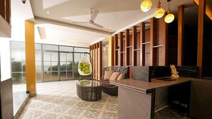 Un interior moderno con una zona de estar, un ventilador de techo y un ventanal grande.