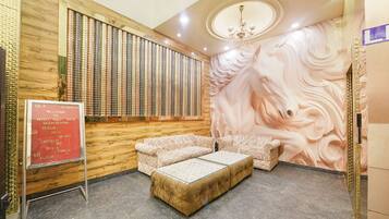 A hotel lobby with a wooden wall, a large mural, a reception desk, and a seating area.