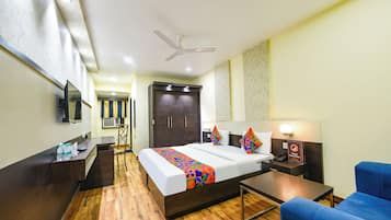 A hotel room with a bed, a desk, a chair, a TV, and a ceiling fan.