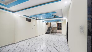 A hallway with a marble floor, a staircase, and a ceiling with a blue and white design. - Fabhotel Radhika Palace (Faizabad)