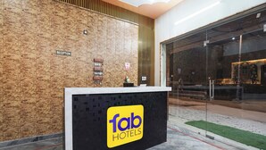 A reception desk with a 'Tab Hotels' sign, a reception area with a wooden wall and a glass door leading to a lobby. - Fabhotel Radhika Palace (Faizabad)