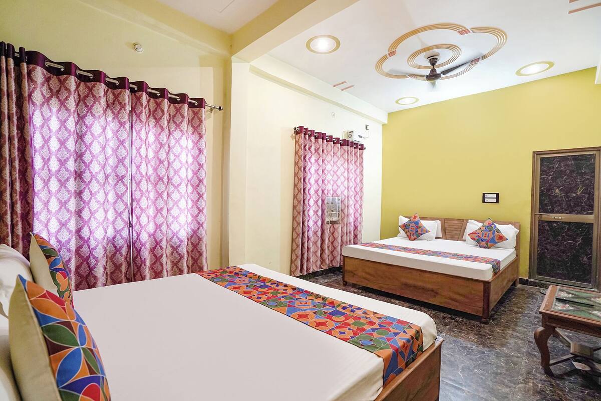 A bedroom with a bed, a wooden headboard, a bedside table, a chair, and a window with curtains.