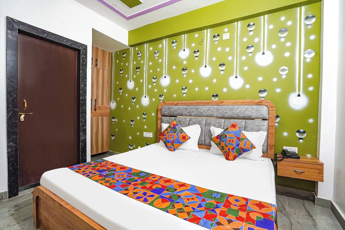 A bedroom with a bed, a nightstand, a wooden door, and a green wall with circular cutouts.