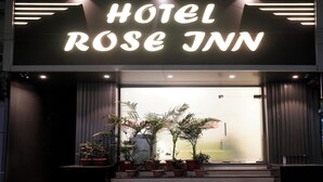The entrance of Hotel Rose Inn with a modern sign, potted plants, and a staircase leading up to the entrance. - Fabexpress Rose Inn (Mumbai)