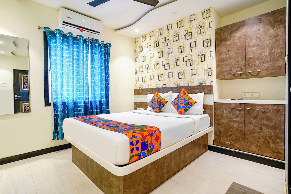 A modern bedroom with a large bed, a wardrobe, and a patterned wall.