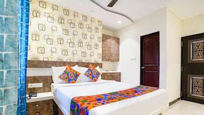 A neatly arranged bedroom with a bed, bedside tables, and a patterned wall. - Fabexpress Rose Inn (Mumbai)