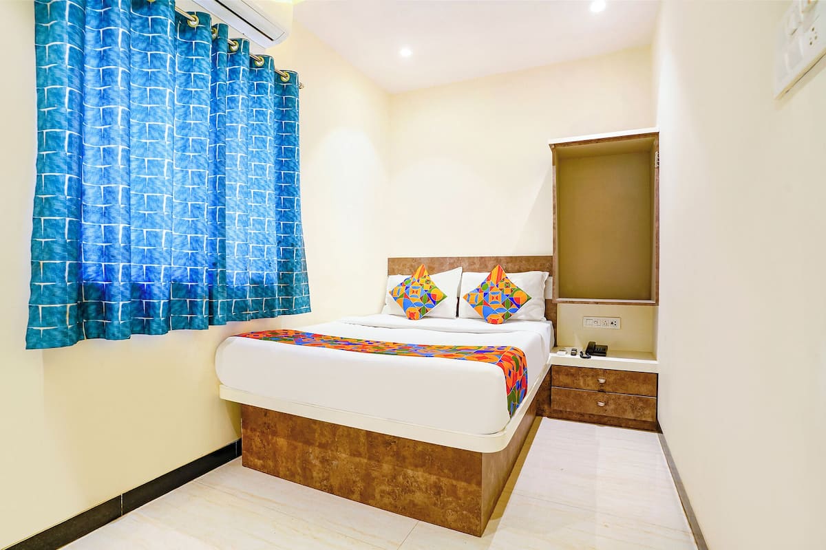 A hotel room with a bed, a mirror, a nightstand, and a bathroom.