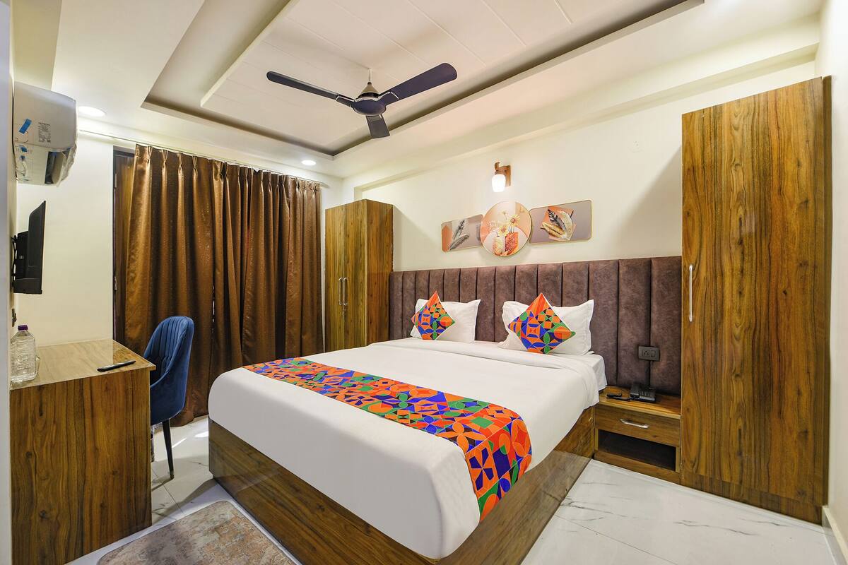 A hotel room with a bed, a desk, a chair, a wardrobe, and a ceiling fan.
