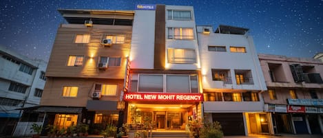 A hotel named "Hotel New Mohit Regency" with a modern facade, multiple windows, and a well-lit entrance.