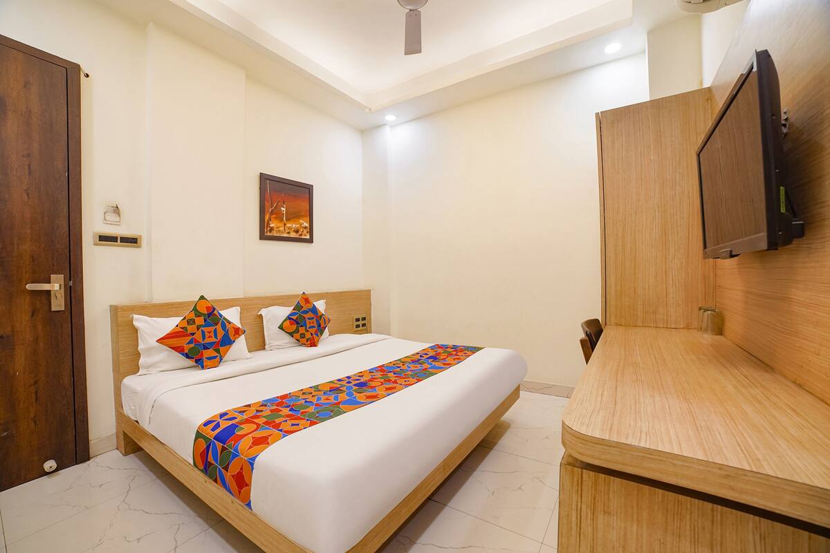 Une chambre d’hôtel avec un lit en bois, un téléviseur fixé au mur et une armoire en bois.